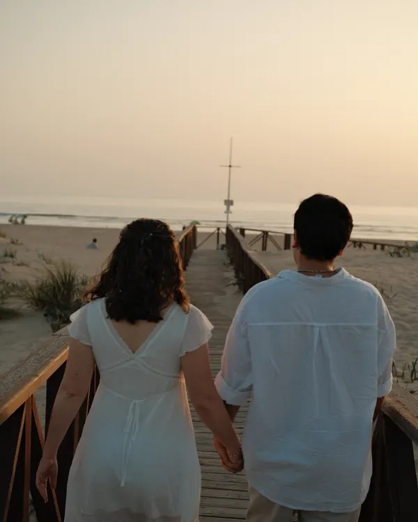Couple walking towards the sea at sunset