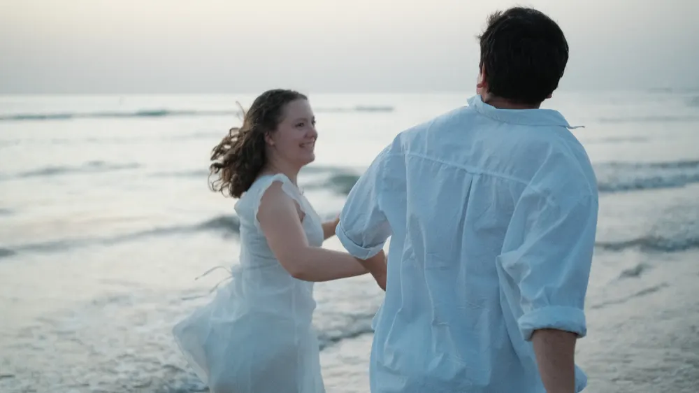 Couple running into the waves at dusk
