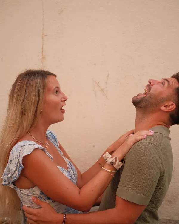 Couple laughing in front of an old wall