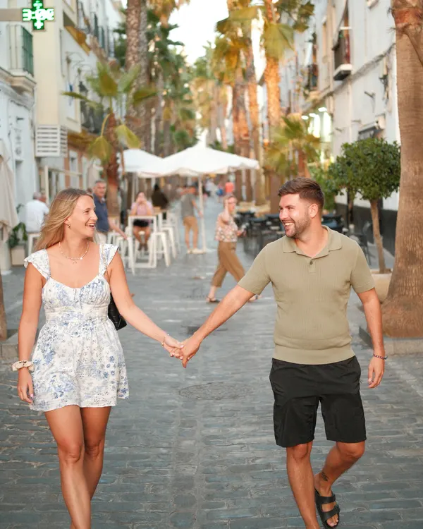 Couple walking hand in hand through a palm-lined street in Cádiz